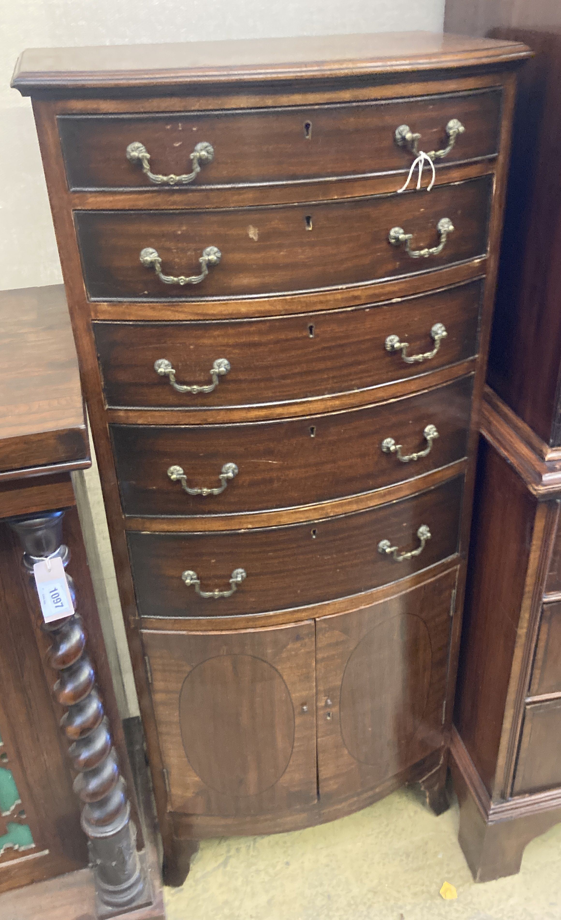 A 1920s Georgian style mahogany bow front chest with cupboard base, length 56cm, depth 36cm, height 135cm